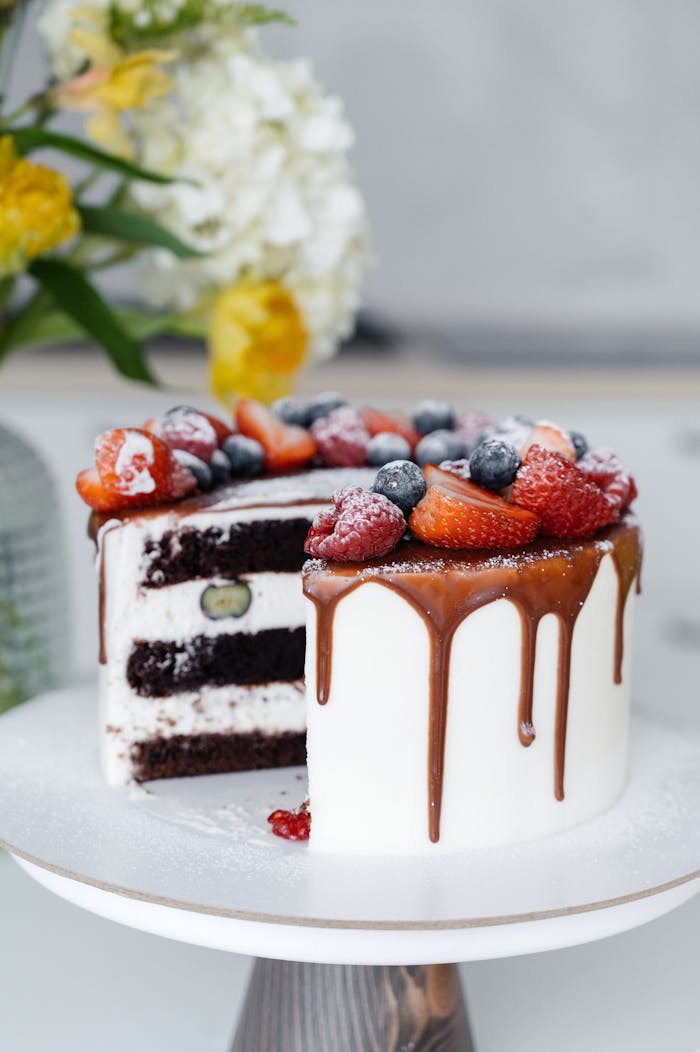 Yummy freshly baked cake with white cream decorated with assorted berries served on tray in light kitchen